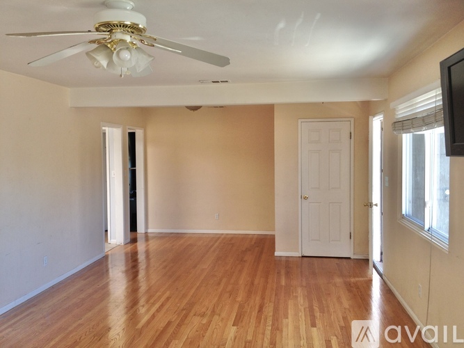 A room with a ceiling fan and wooden floors.