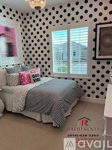 A bedroom with a bed and a window with a view of a house.