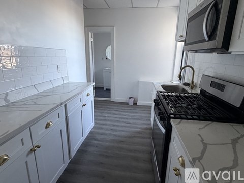 A kitchen with white cabinets and a black stove top oven.