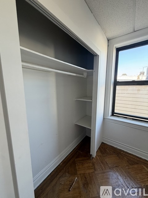 Empty room with a window and wooden flooring.