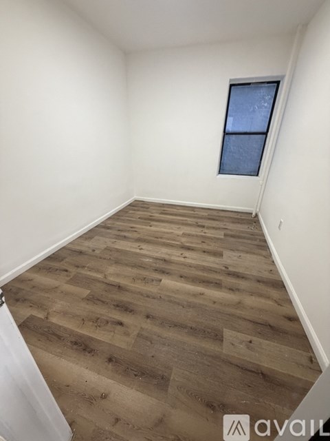 A room with wooden flooring and a window.