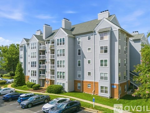 A large apartment complex with a parking lot in front.