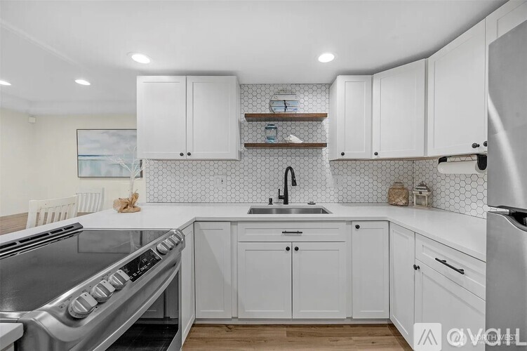 A modern kitchen with white cabinets and a stainless steel oven.