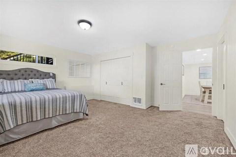 A bedroom with a bed, carpeted floor, and a window with blinds.