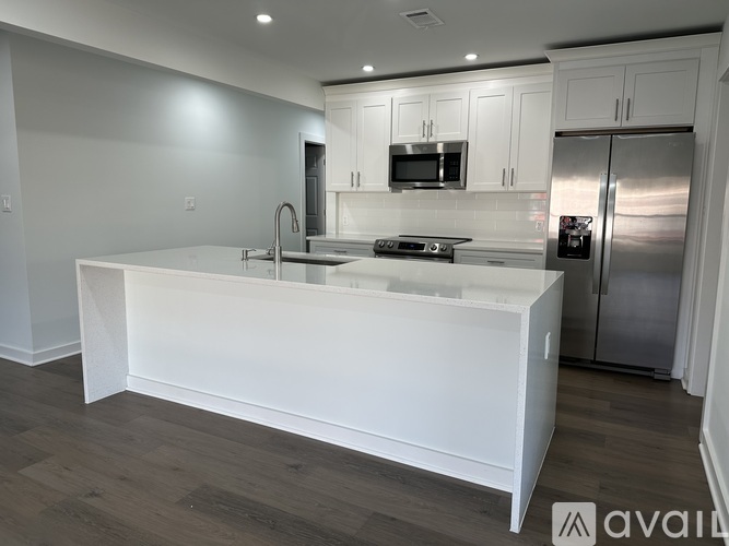 A modern kitchen with a white island and stainless steel appliances.
