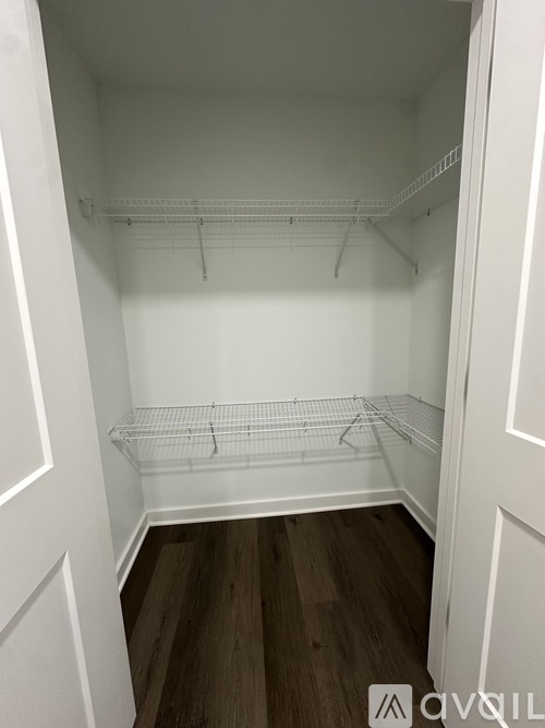 A white walk-in closet with wooden floors and shelving.