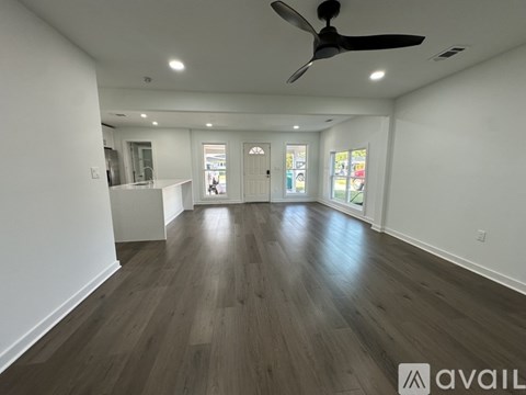 A spacious room with a ceiling fan and wooden flooring.