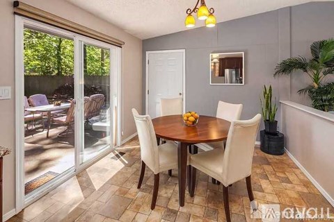 A dining room with a table and chairs and a plant.