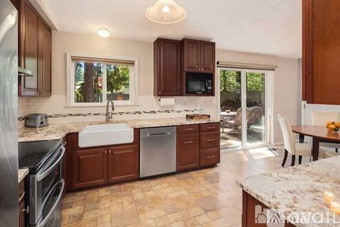A kitchen with brown cabinets and a marble countertop.