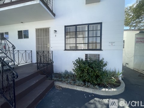 A white building with a black gate and a window with bars.