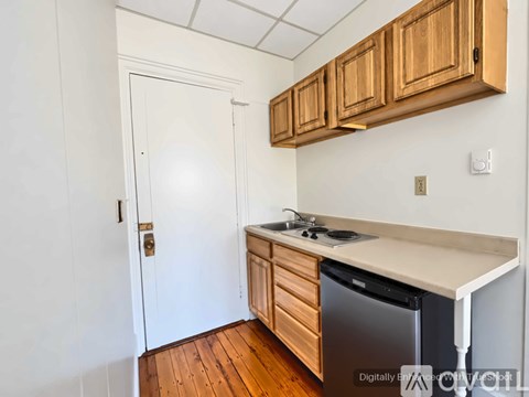 A kitchen with wooden cabinets and a black dishwasher.