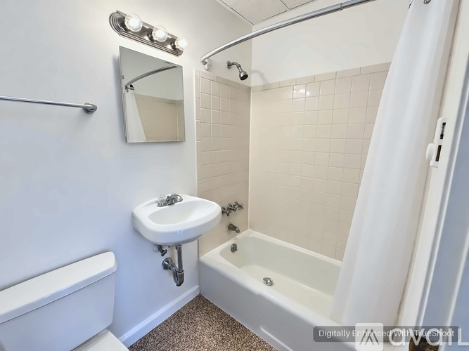 A white bathroom with a sink, mirror, and bathtub.