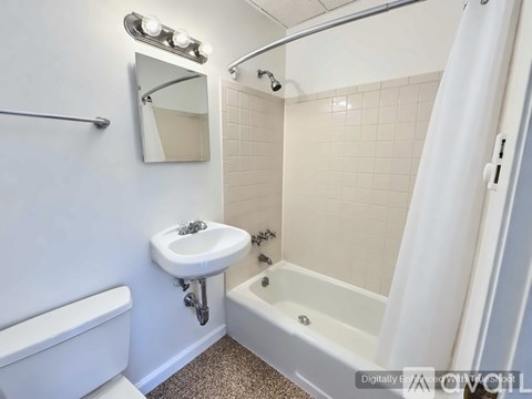 A white bathroom with a sink, mirror, and bathtub.