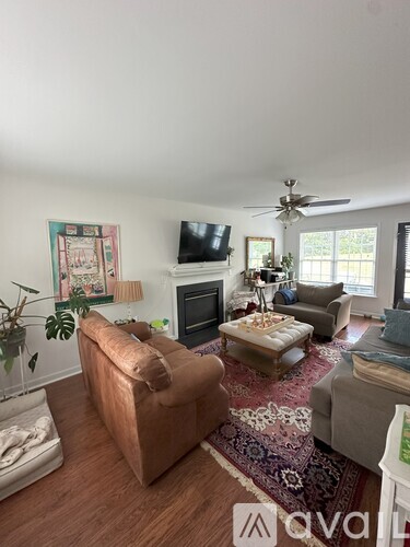 A living room with a brown sofa, a rug, and a ceiling fan.