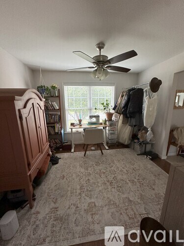 A room with a ceiling fan and a rug on the floor.
