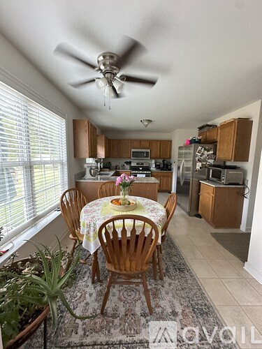 A dining room with a table set for four with a pink flower on the table.