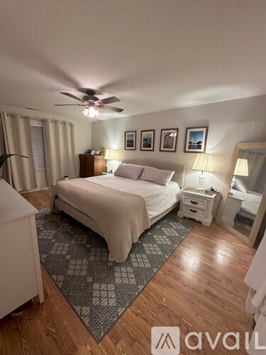 A bedroom with a bed, nightstands, and pictures on the wall.
