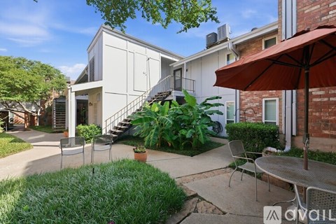 A patio with a table and chairs is surrounded by a well-kept garden.
