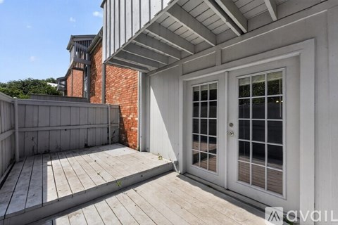 A wooden deck leads to a glass door on a white building.