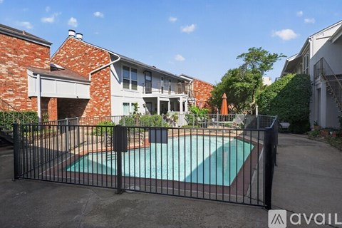 A black fence surrounds a green pool in front of a house.