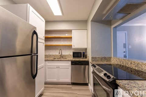 A kitchen with a stainless steel refrigerator and a granite countertop.