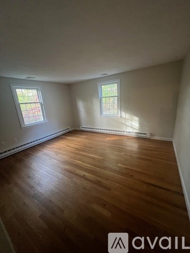 A room with wooden floors and two windows.