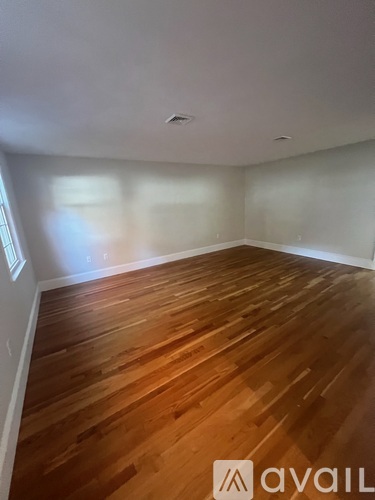 A room with wooden flooring and white walls.