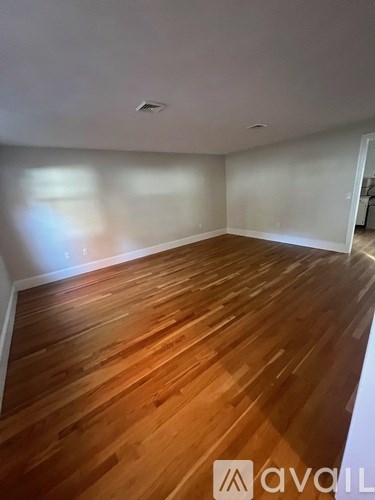 A room with wooden flooring and white walls.