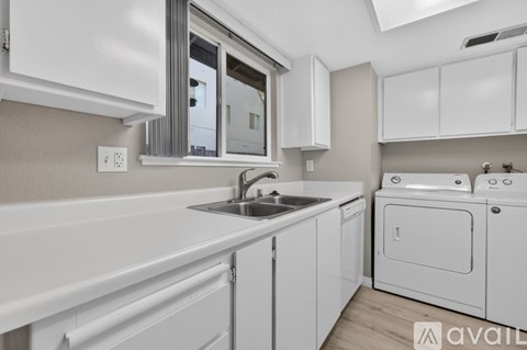 A modern kitchen with white cabinets and appliances.