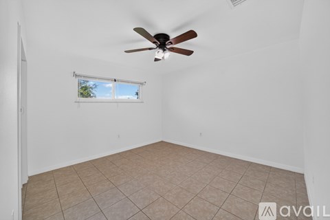 A room with a ceiling fan and a window with a view of trees.