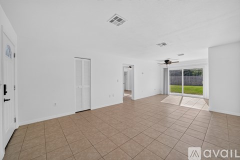 A spacious room with tiled flooring and a ceiling fan.