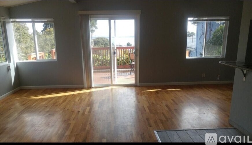 A room with wooden floors and a balcony with a railing.