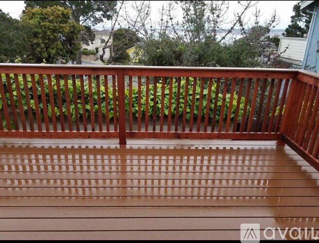 A wooden deck with a railing and a view of the backyard.
