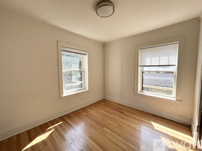 A room with wooden floors and two windows.