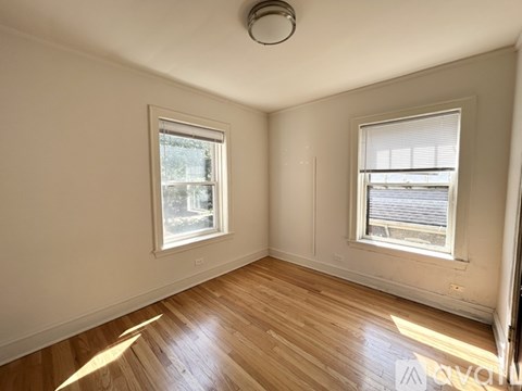 A room with wooden floors and two windows.