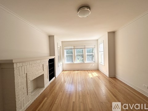 A spacious room with wooden floors and a fireplace.