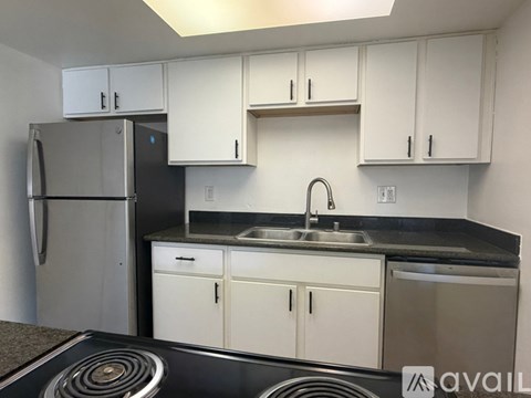 A kitchen with white cabinets and a stainless steel refrigerator.