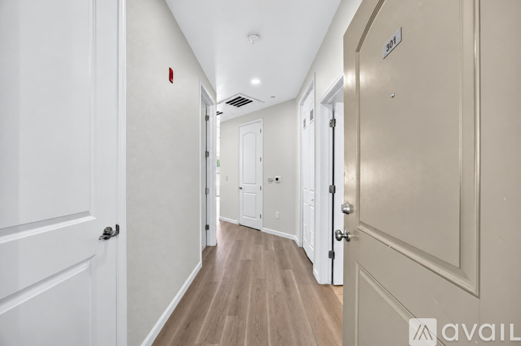 A long hallway with doors on both sides and a sign that says "avail" on the wall.