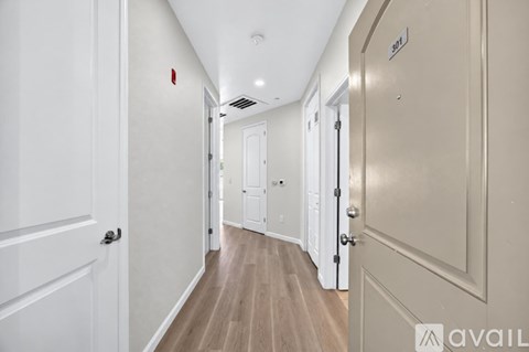 A long hallway with doors on both sides and a sign that says "avail" on the wall.