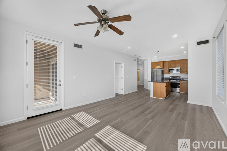 A spacious living room with a ceiling fan and striped rug on the floor.