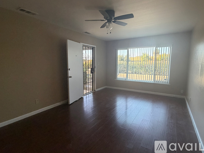 A room with a ceiling fan and sliding glass doors.
