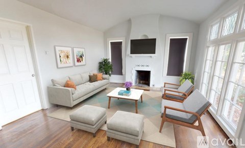 A living room with a grey couch, a white fireplace, and a wooden floor.