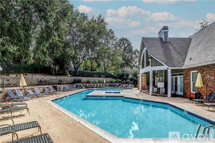 A pool with lounge chairs and a house in the background.