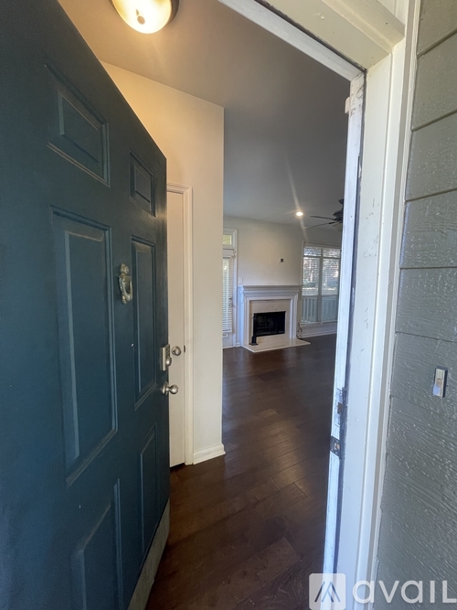 A hallway with a dark blue door and a white door on the other side.