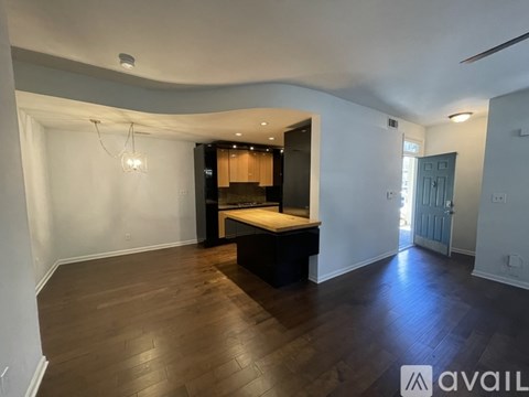 A spacious room with wooden floors and a bed in the corner.