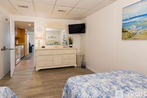 A bedroom with a bed, dresser, and a painting of a beach scene on the wall.