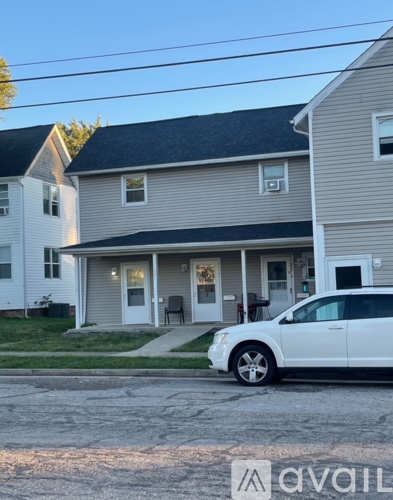 A white car is parked in front of a house.