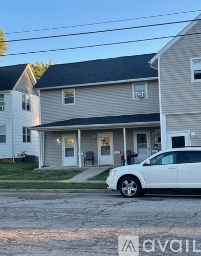 A white car is parked in front of a house.