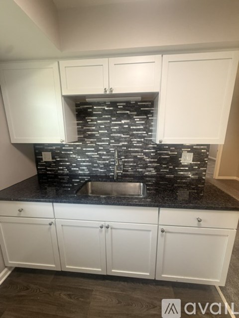 A kitchen with white cabinets and a black countertop.