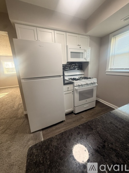 A kitchen with a white fridge, stove, and microwave.